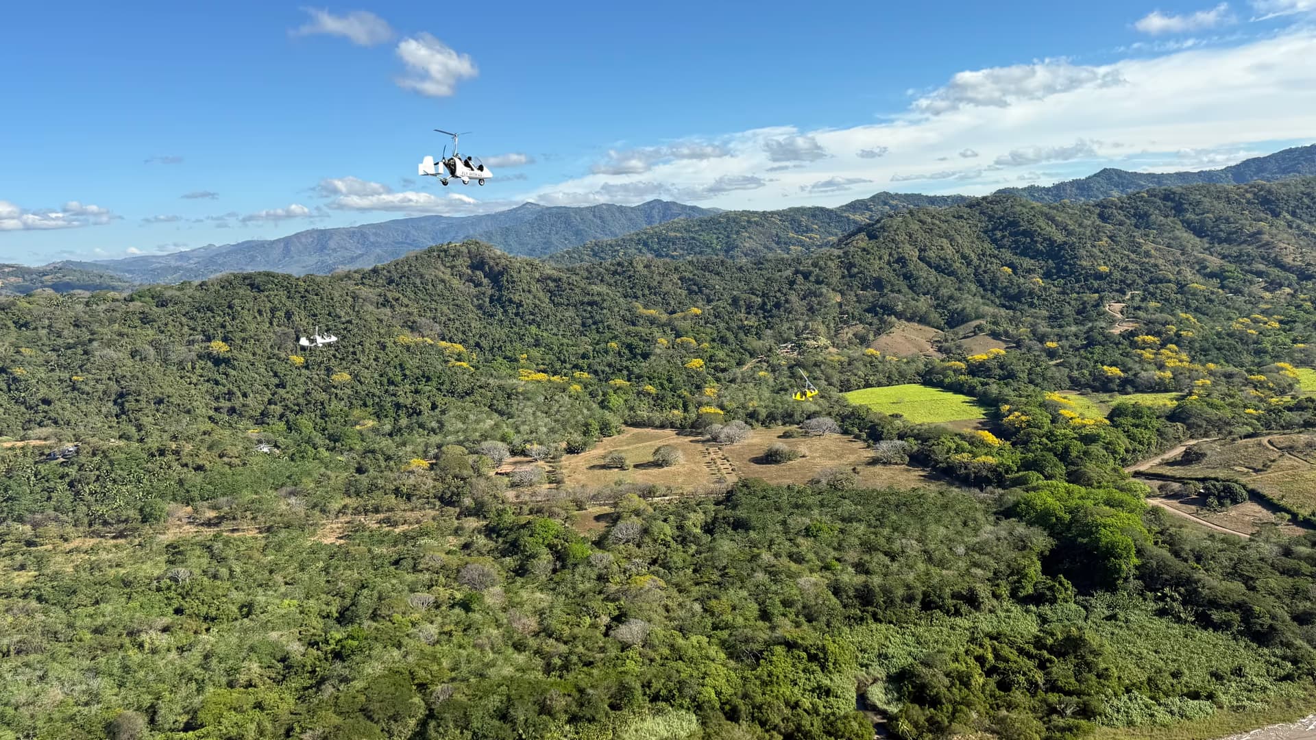 Three gyrocopters in formation over green Guanacaste hills